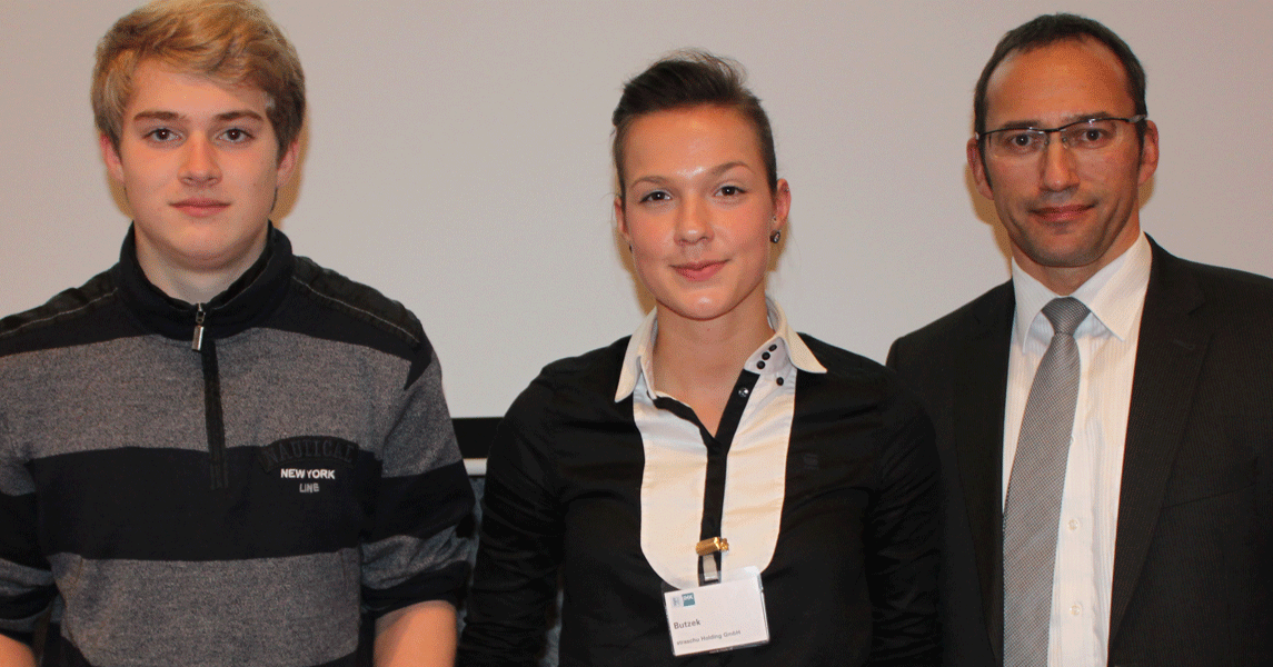 Ein blonder junger Mann, eine brünette Frau und ein Mann in Anzug und mit Brille stehen nebeneinander und blicken in die Kamera.