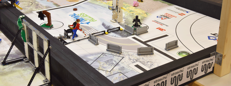 Ein Tisch mit einem hohen Rand, der mit straschu Banner verkleidet ist, und auf dem Tisch stehen verschiedene Konstruktionen aus Lego gebaut.
