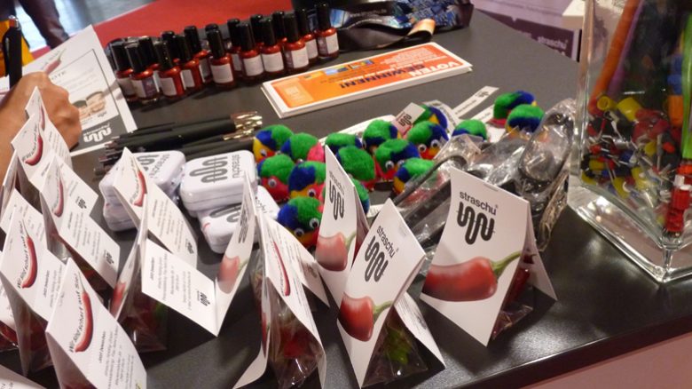 Verschiedene Giveaways sind auf einem Tisch auf der Jobmesse aufgereiht.