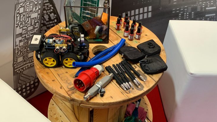 Auf einer Kabeltrommel liegen Giveaways wie Kugelschreiber und Nagellackflaschen und Musterexponate und Produkte von straschu für die Jobmesse in Bremen.