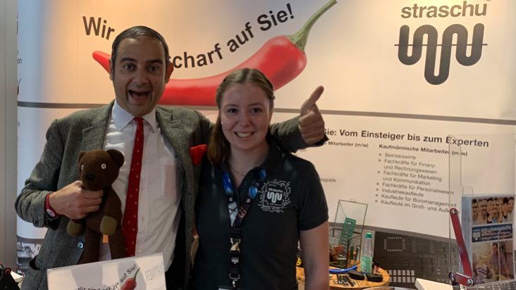 Eine straschu Mitarbeiterin und der Charakter Mr Bean stehen am Messetand von strasch auf der Jobmesse in Bremen