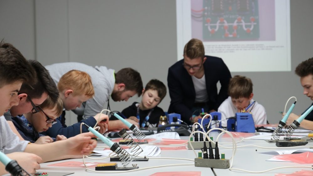 Eine Gruppe von Kindern lötet am Zukunftstag an einem Lötprojekt.