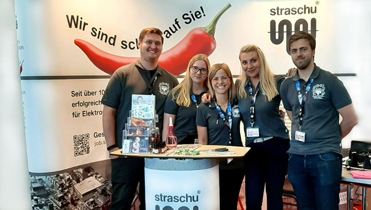 Das straschu Standteam steht vor dem Messecounter auf der vocatium Messe und lächelt