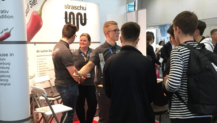 Auf der vocatium Messe in Bremen stehen Schüler vor dem straschu Messestand und das Standteam redet mit ihnen.