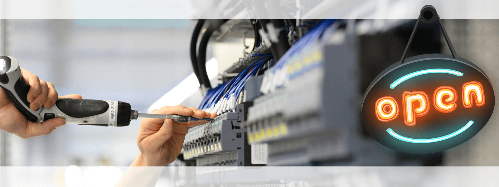 An einem Schaltschrank wird mit einer Bohrmaschine gebaut und rechts hängt ein schwarzes Schild mit dem farbigen Schriftzug open.