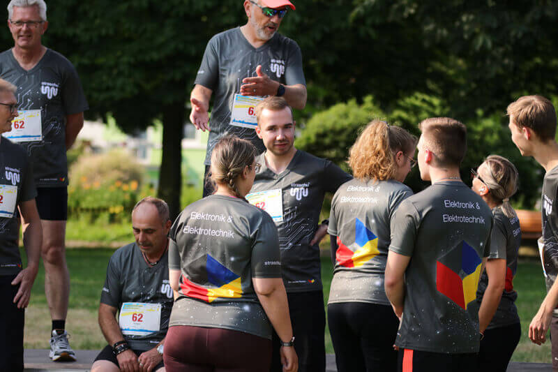 Eine Gruppe von Menschen in straschu-Shirts steht zusammen und redet.