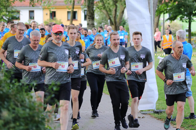 Menschen in straschu-Shirts laufen bei dem Firmenlauf mit.