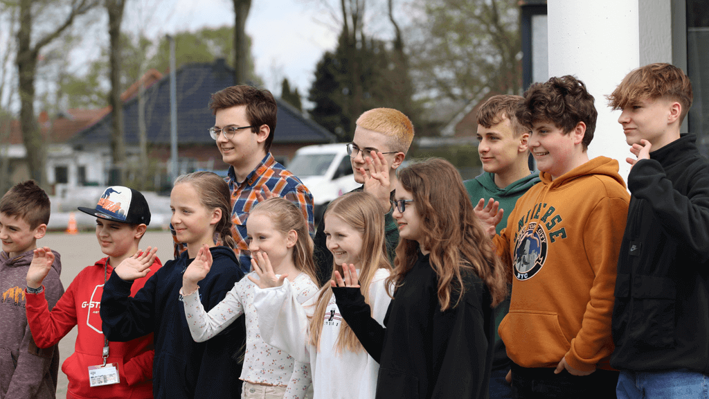 Eine Gruppe von Kindern winken jemanden außerhalb des Bildes am Zukunftstag zu.