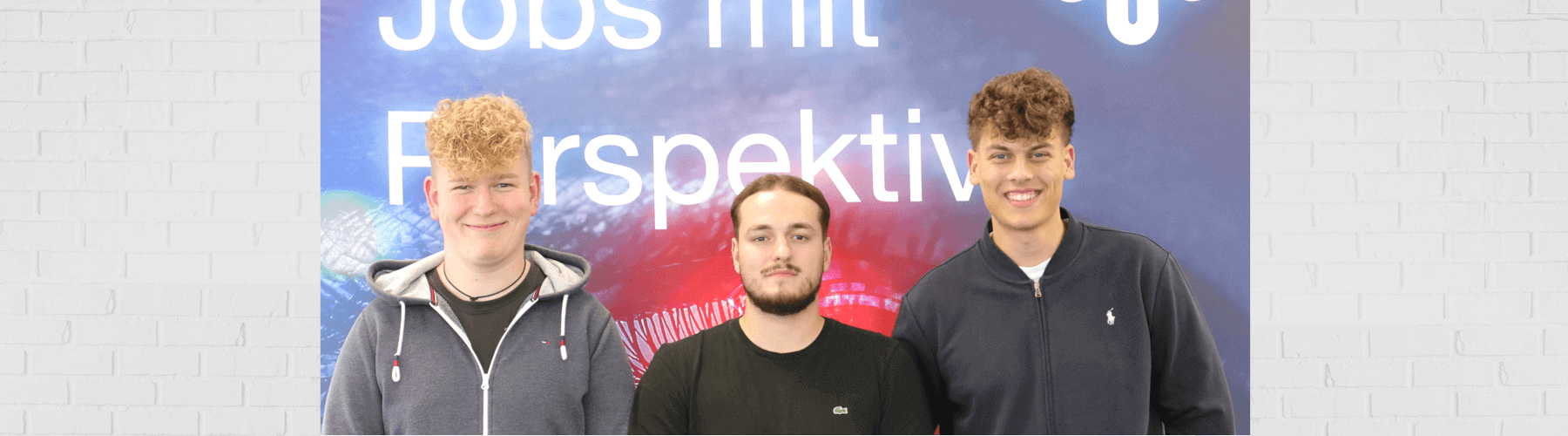 Drei Ausbildungsbotschafter stehen vor einem Plakat mit der Aufschrift Jobs mit Perspektive und lächeln in die Kamera.