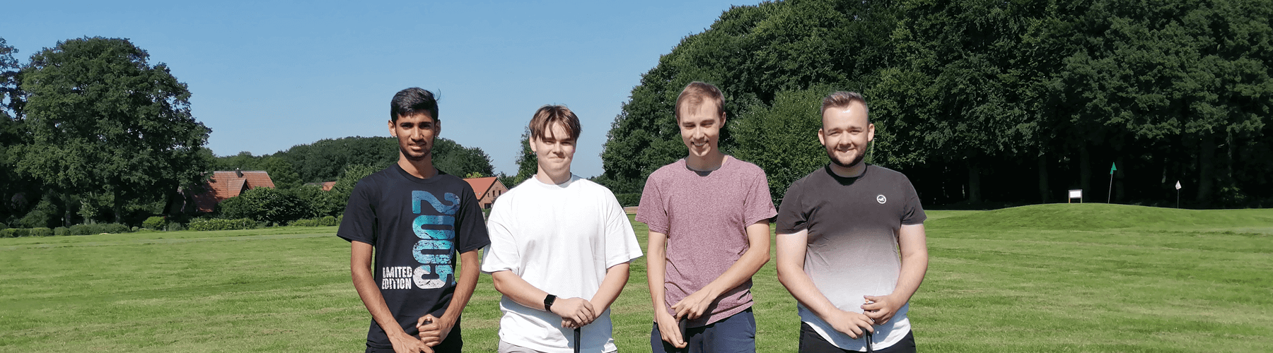 4 Männer bei einem Ausflug auf einen Golfplatz lächeln ins Bild