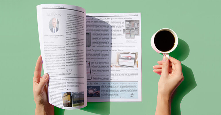 Ein Magazin wird von einer Hand aufgeschlagen. Die andere Hand hält einen Kaffeebecher.
