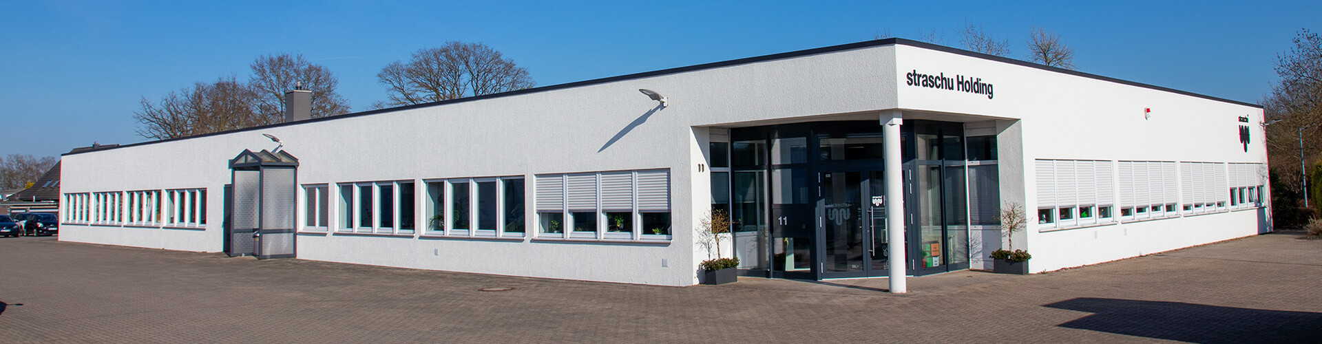 Ansicht auf ein weißes einstöckiges Gebäude mit Flachdach.