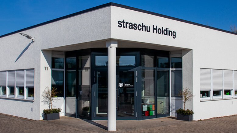 Der Eingang eines weißen Gebäudes mit dem Schriftzug "straschu Holding".