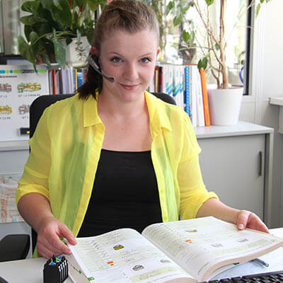 Eine junge Frau, die eine Ausbildung zur Kauffrau im Groß- und Außenhandelsmanagement macht, blättert in einem Katalog. 