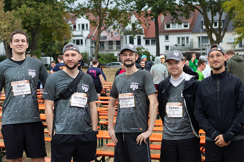 Fünf Männer in Firmen-T-Shirts sind beim Firmenlauf.